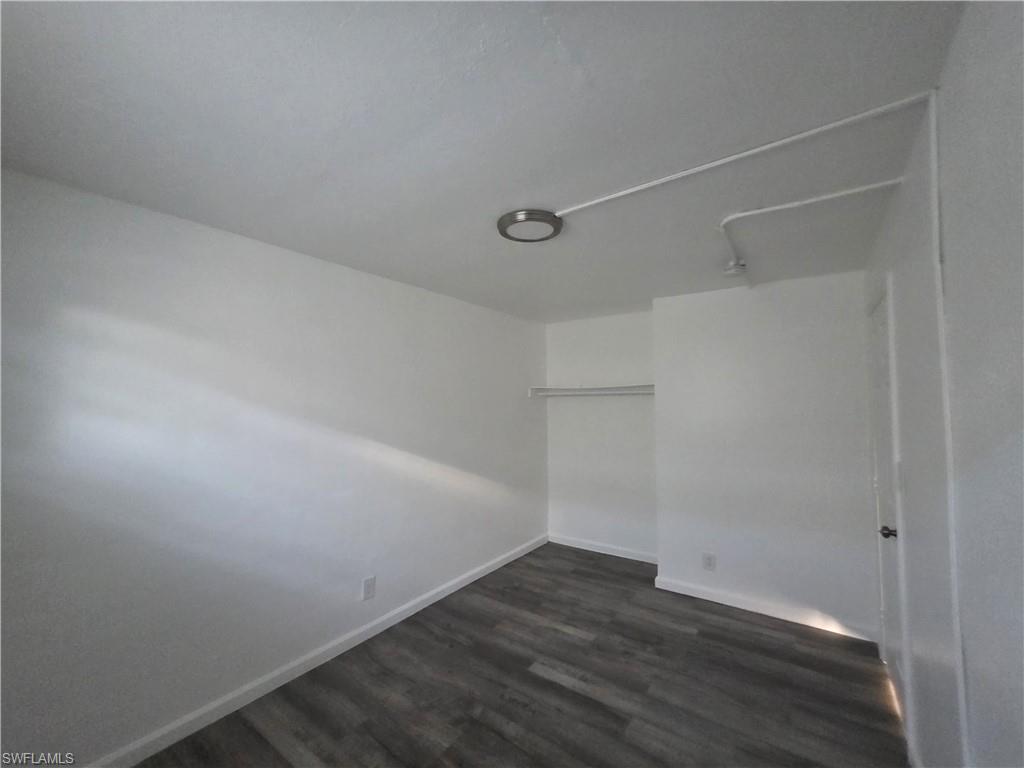 Unfurnished bedroom featuring dark wood-type flooring and a closet