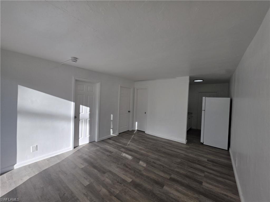 Empty room featuring dark wood-style floors and baseboards