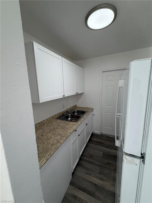 Kitchen featuring freestanding refrigerator, white cabinetry, and dark wood-style flooring