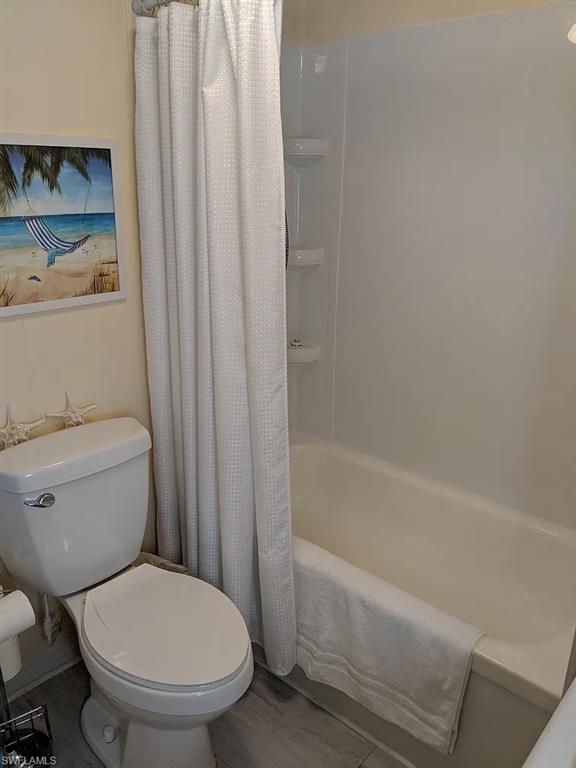 Full bathroom featuring toilet and shower / bath combo with shower curtain