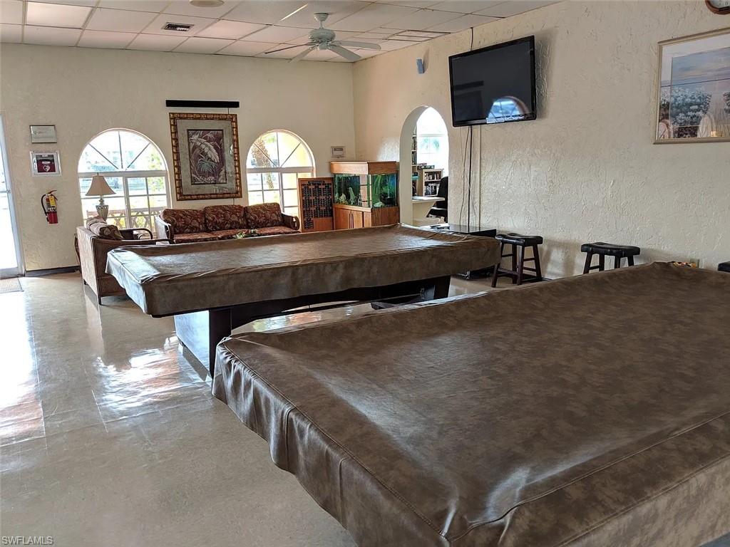 Recreation room featuring a textured wall, billiards table, a paneled ceiling, ceiling fan, and arched walkways