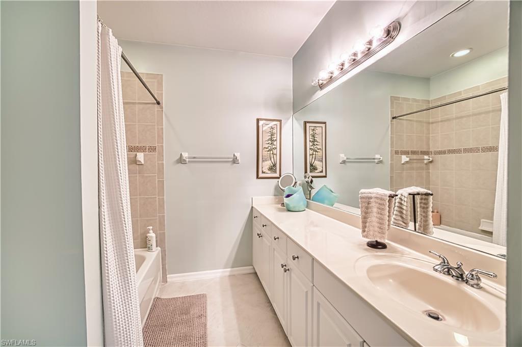 Full bath featuring vanity, shower / bathtub combination with curtain, and light tile patterned flooring
