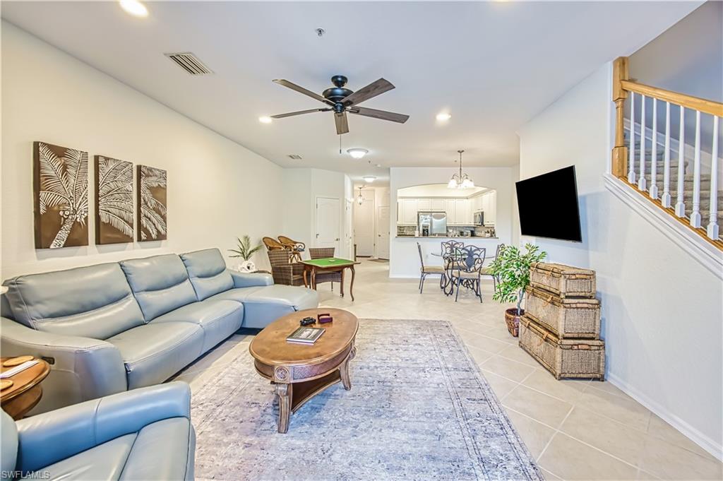 Living area with a ceiling fan, light tile patterned floors, suspended lighting, and arched walkways