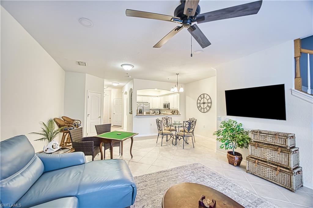 Living room featuring arched walkways, ceiling fan, light tile patterned floors, and hanging lights