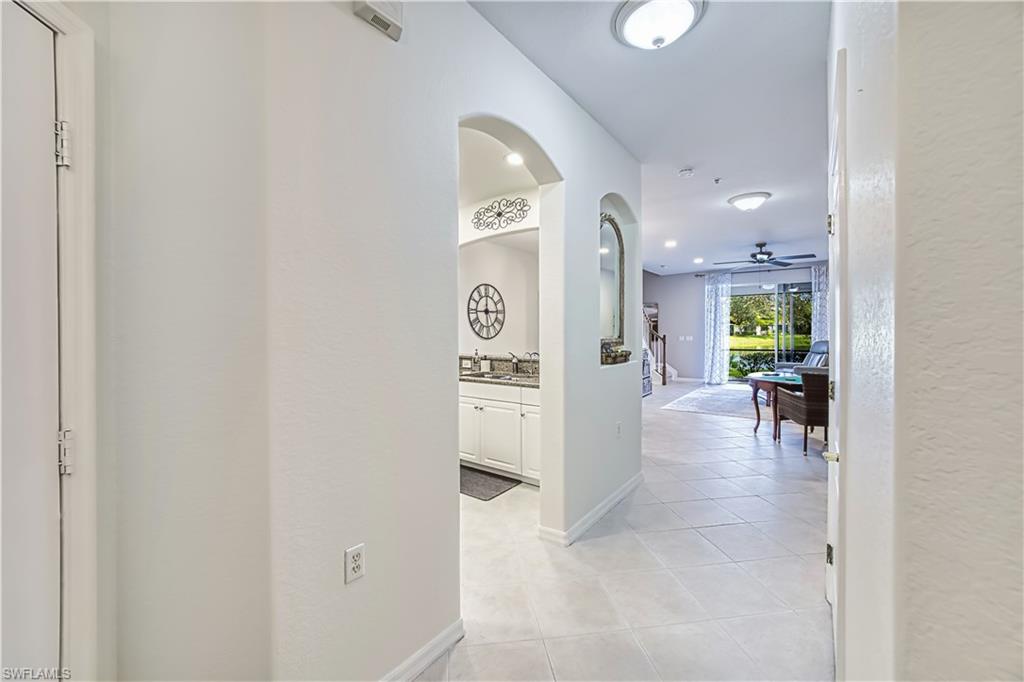 Hallway with light tile patterned floors, arched walkways, recessed lighting, and a textured wall