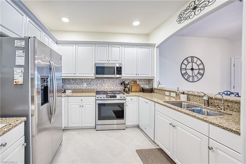 Kitchen featuring stainless steel appliances, light stone counters, white cabinets, and recessed lighting