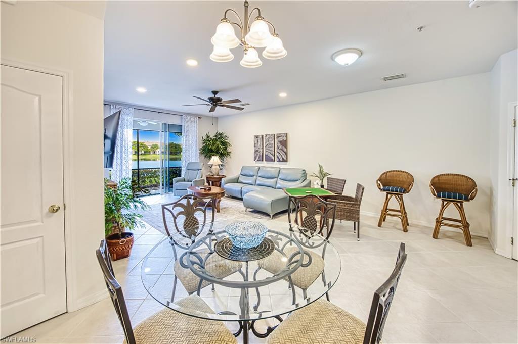 Dining space featuring a chandelier, light tile patterned flooring, ceiling fan, and expansive windows
