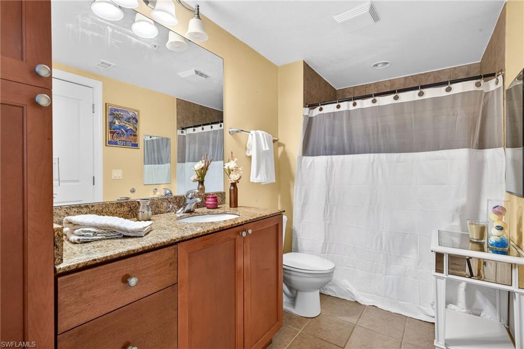 Full bath with light tile patterned flooring, vanity, and a shower with shower curtain
