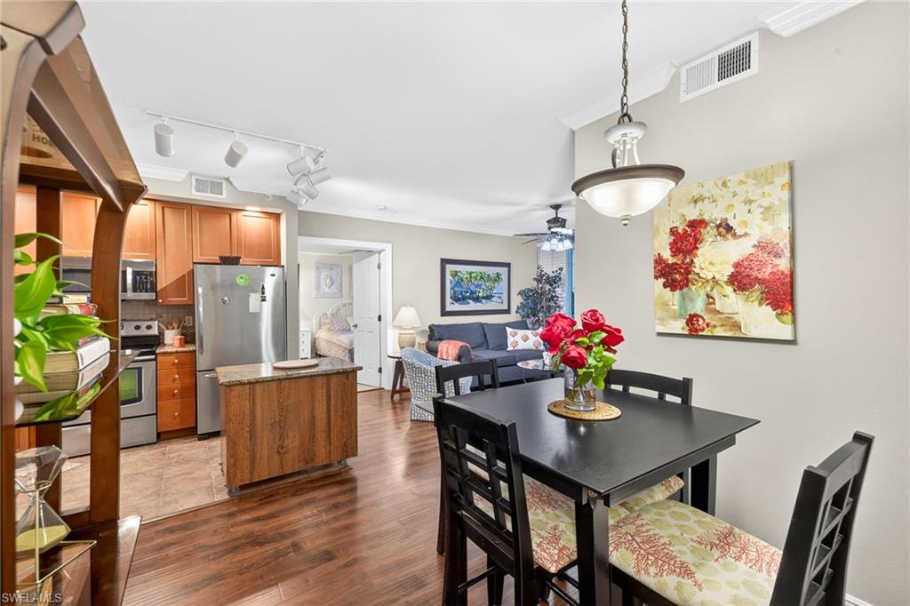 Dining room with ornamental molding, dark wood-type flooring, rail lighting, and ceiling fan