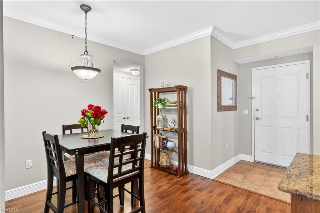 Dining room with crown molding and dark wood-style flooring