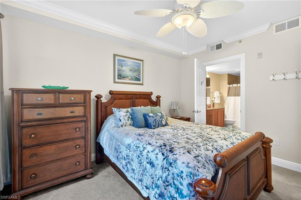 Bedroom with crown molding, carpet floors, a ceiling fan, and ensuite bath