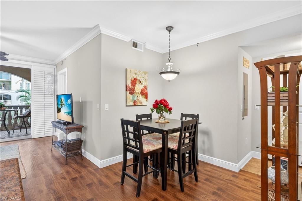 Dining area with ornamental molding and dark wood-style flooring