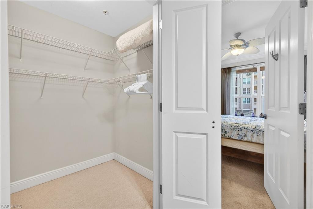 Walk in closet with a ceiling fan and light carpet