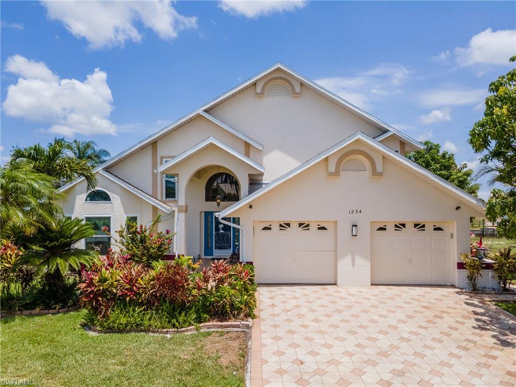 View of front of property featuring stucco siding, decorative driveway, a front yard, and a garage
