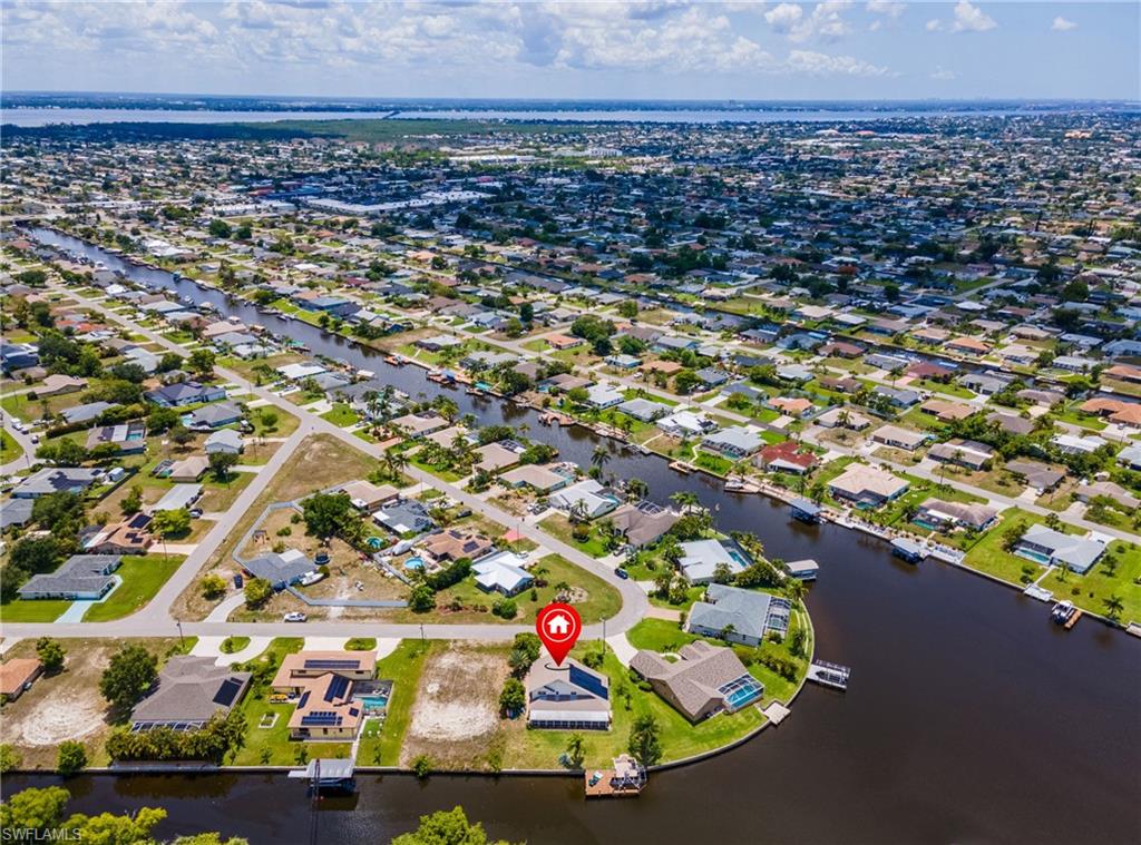 Aerial view of property and surrounding area featuring nearby suburban area and a large body of water