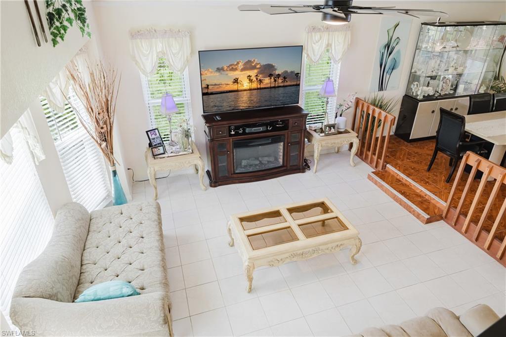 Living area featuring ceiling fan, light tile patterned floors, and a glass covered fireplace