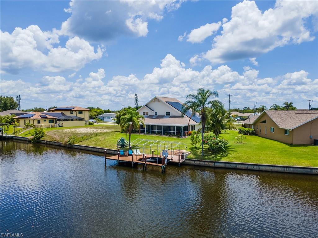 Dock featuring a water view, a residential view, boat lift, and a lawn