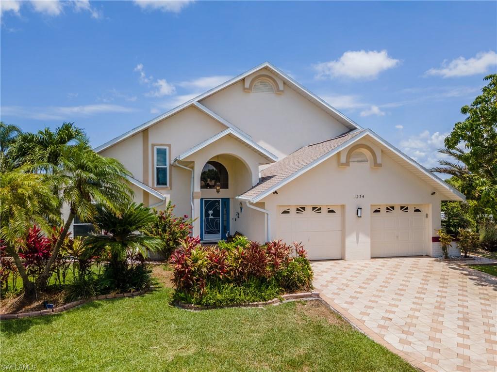 View of front of property featuring a front lawn, stucco siding, decorative driveway, and an attached garage