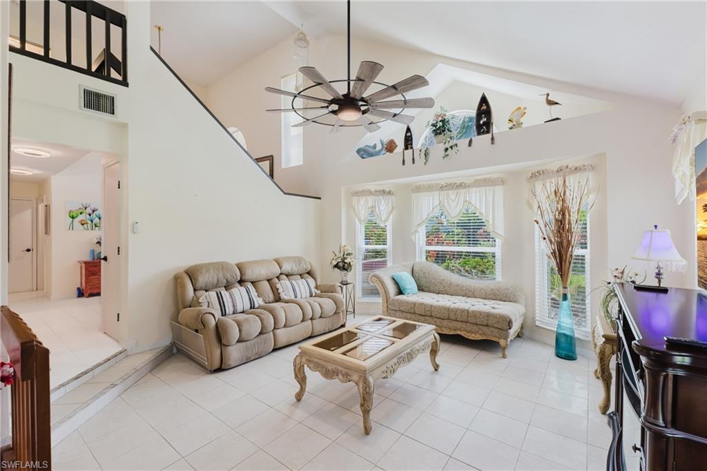 Tiled living area with ceiling fan and a high ceiling