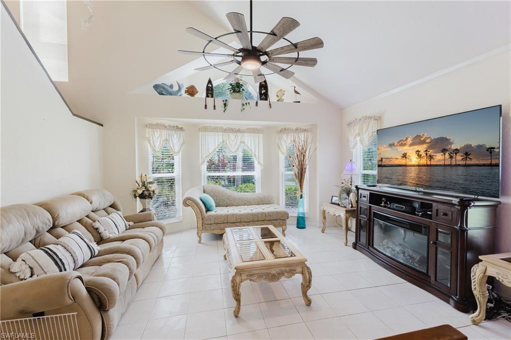 Living room with a ceiling fan, light tile patterned floors, and lofted ceiling
