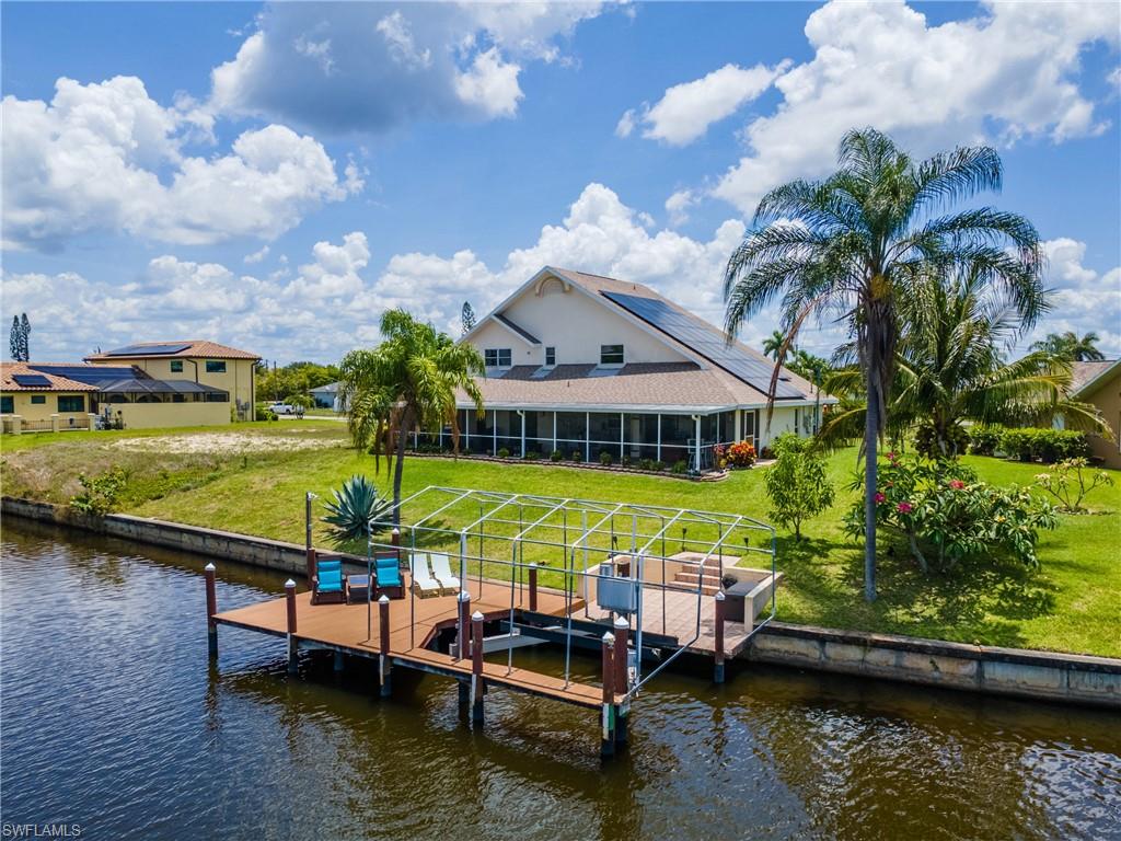 Dock featuring a water view, a sunroom, boat lift, and a yard
