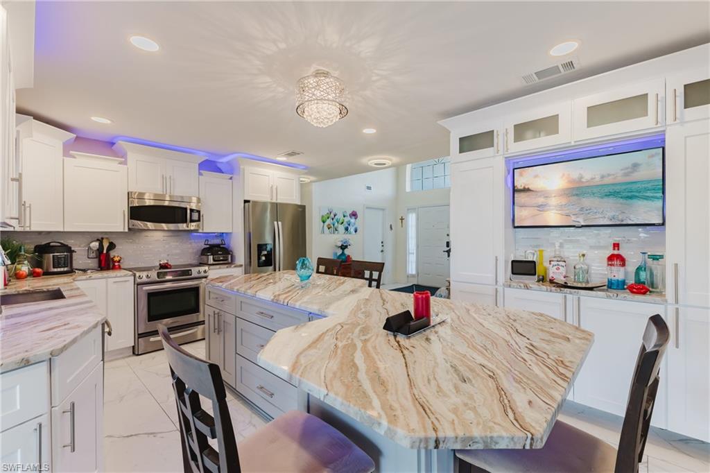 Kitchen featuring stainless steel appliances, a breakfast bar area, a kitchen island, white cabinetry, and recessed lighting