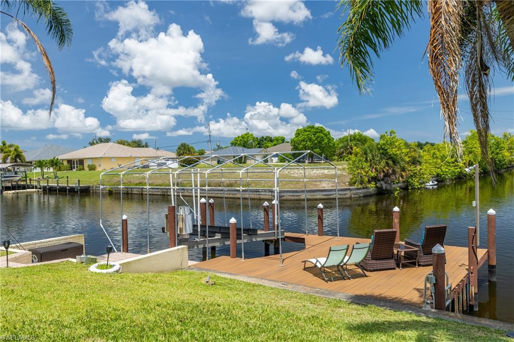 Dock area with boat lift, a water view, and a yard
