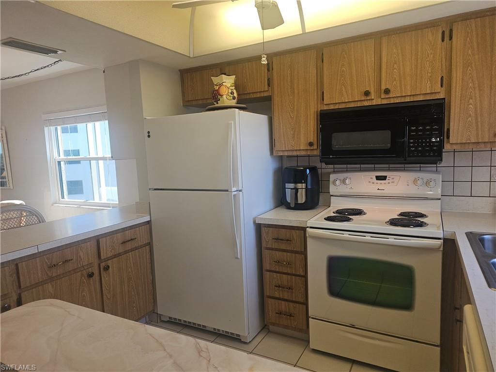 Bright & Sunny Open Kitchen with white appliances, light marbled countertops, wood finish cabinetry, and tile backsplash