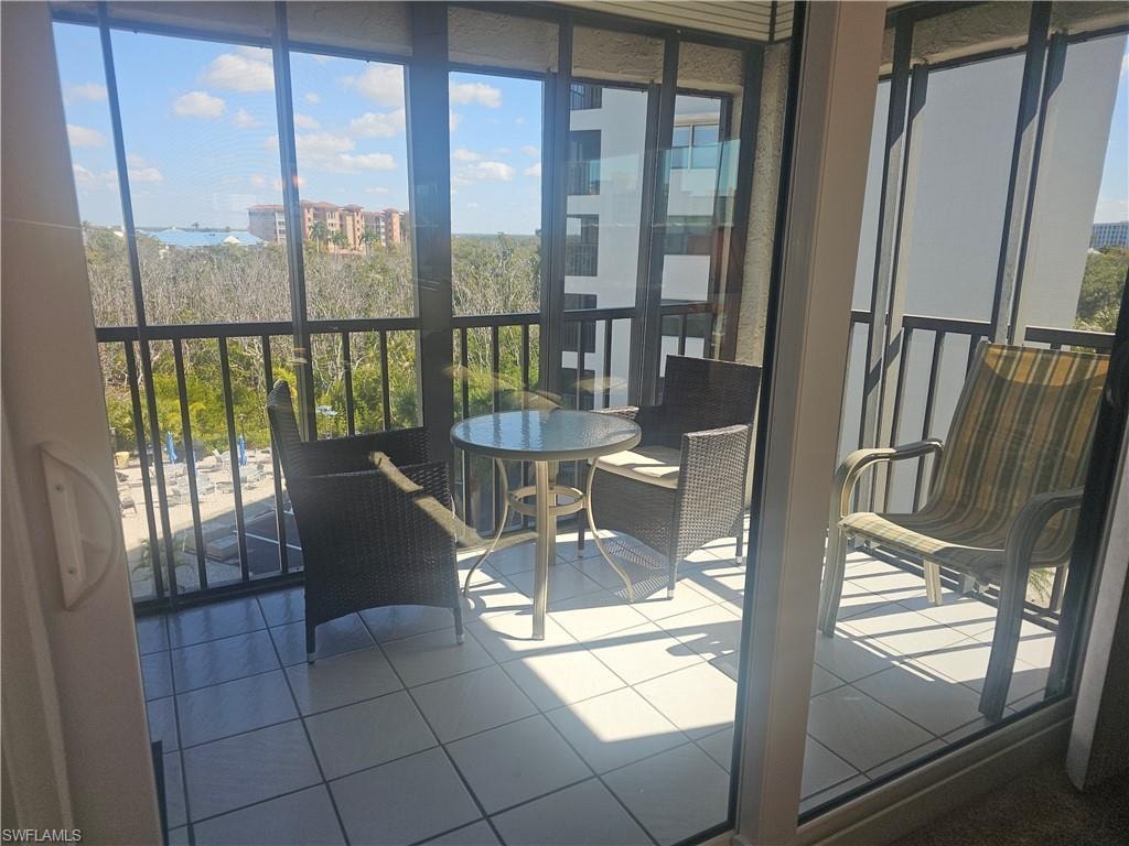 Bright corner screened lanai with tiled floors, impact sliders, storm shutters, and just enough shade to create a relaxed space to unwind after a day at the beach.
