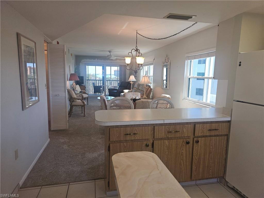 View from kitchen over island to dining/living, corner screened lanai overlooking community pool & preserves towards Estero Bay.
