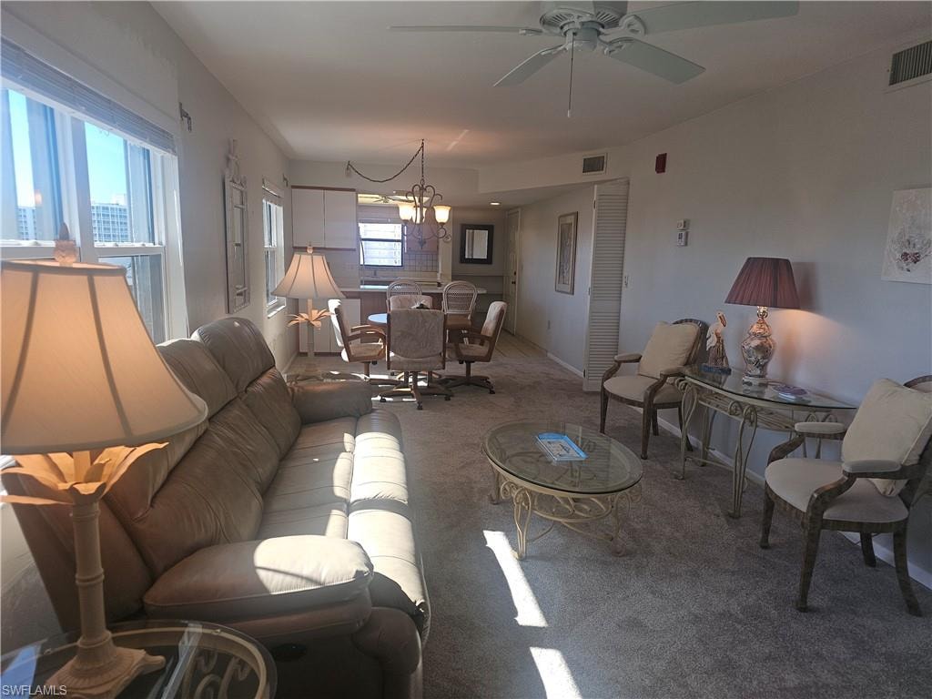 Living area featuring carpet, a chandelier, and ceiling fan