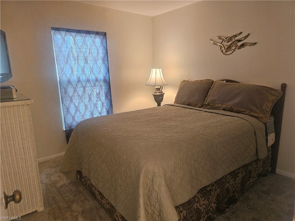 Guest Bedroom featuring  window onto front balcony towards gulf beach, neutral carpet flooring, closet and hall to guest full bath and laundry.