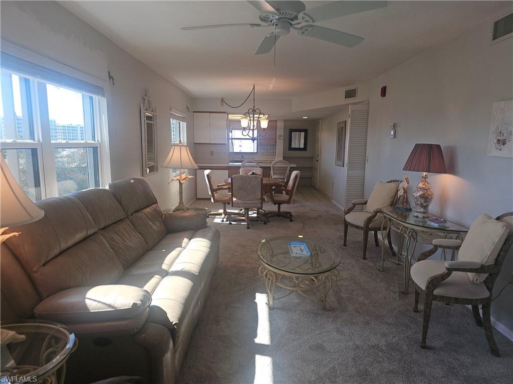 Living room featuring carpet floors, ceiling fan, and a chandelier