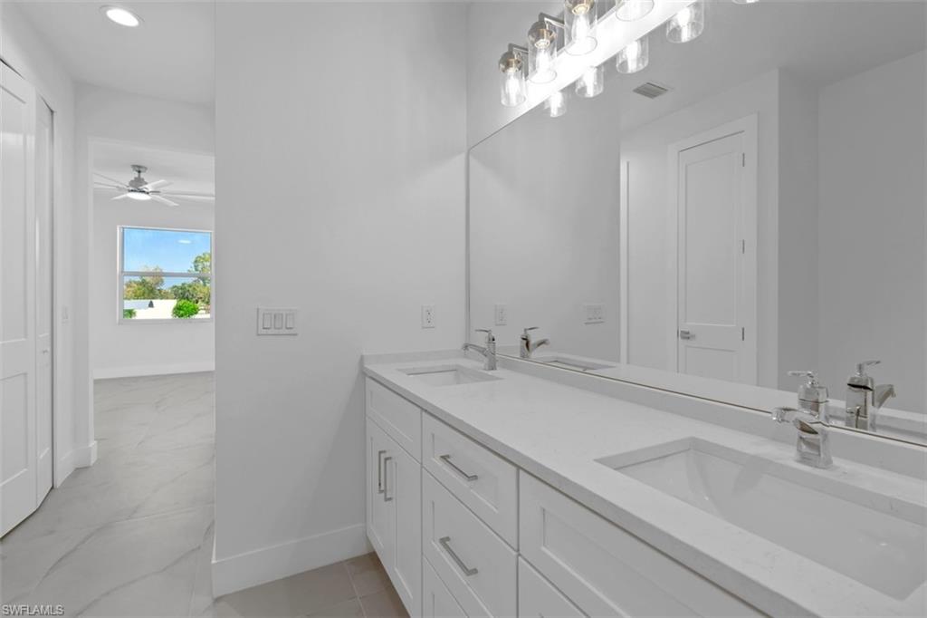 Full bathroom with baseboards, visible vents, a sink, and double vanity