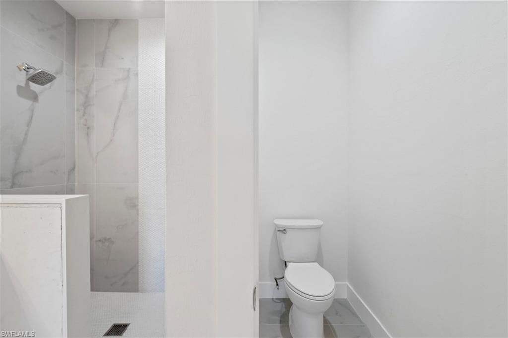 Full bath featuring a marble finish shower, toilet, baseboards, marble finish floor, and visible vents