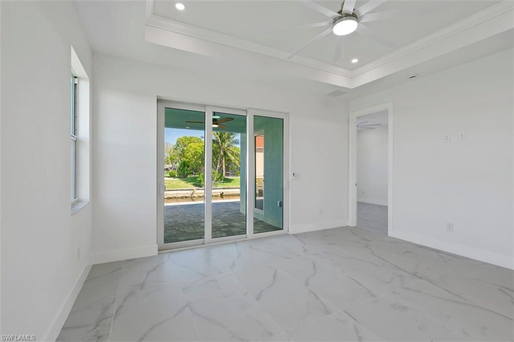 Empty room with baseboards, ceiling fan, and a raised ceiling