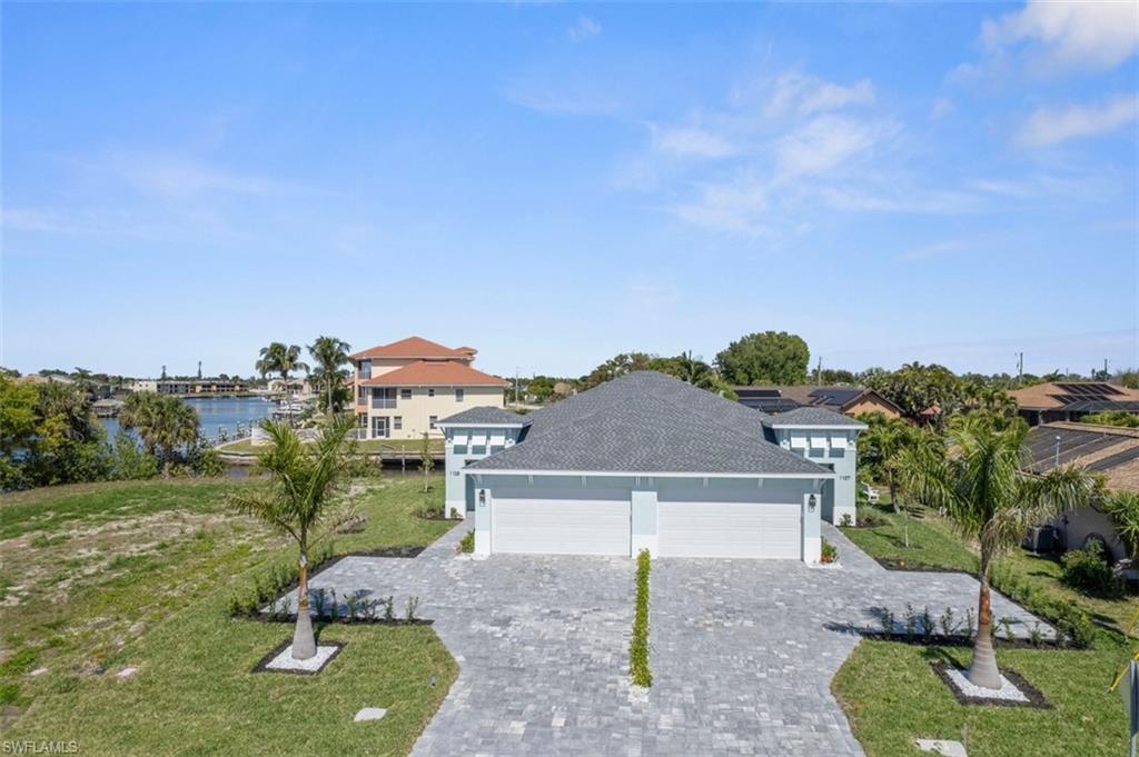 View of front of home featuring a water view, a garage, a front yard, and decorative driveway