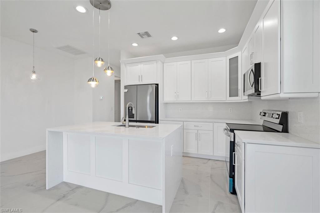 Kitchen with visible vents, marble finish floor, a kitchen island with sink, appliances with stainless steel finishes, and white cabinetry