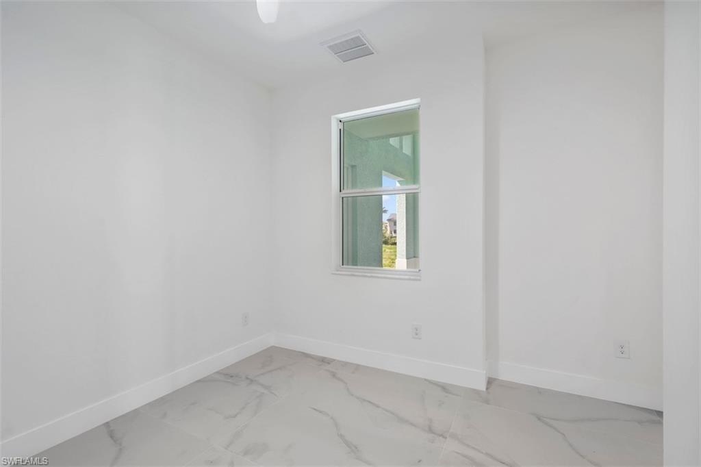 Spare room featuring marble finish floor, baseboards, and visible vents