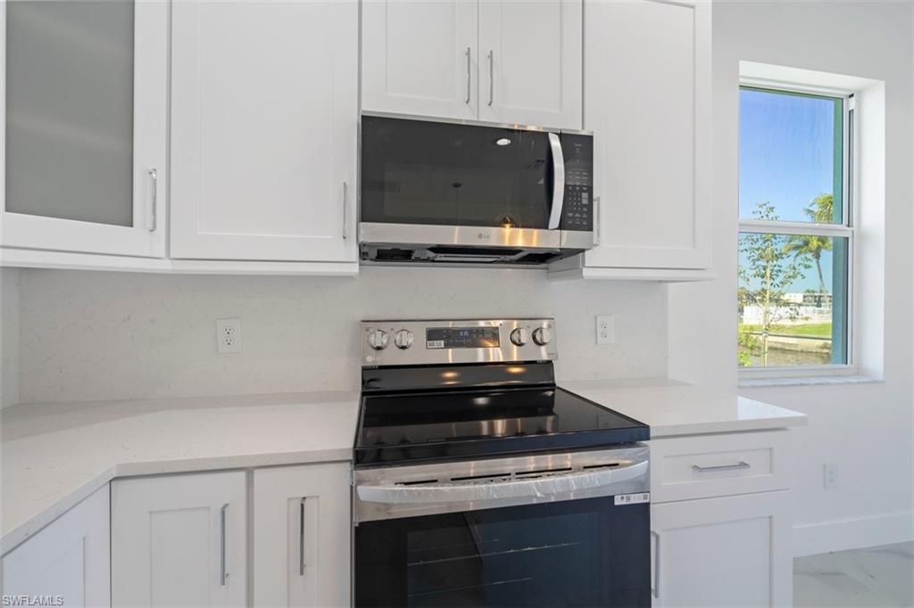 Kitchen with glass insert cabinets, white cabinetry, and stainless steel appliances