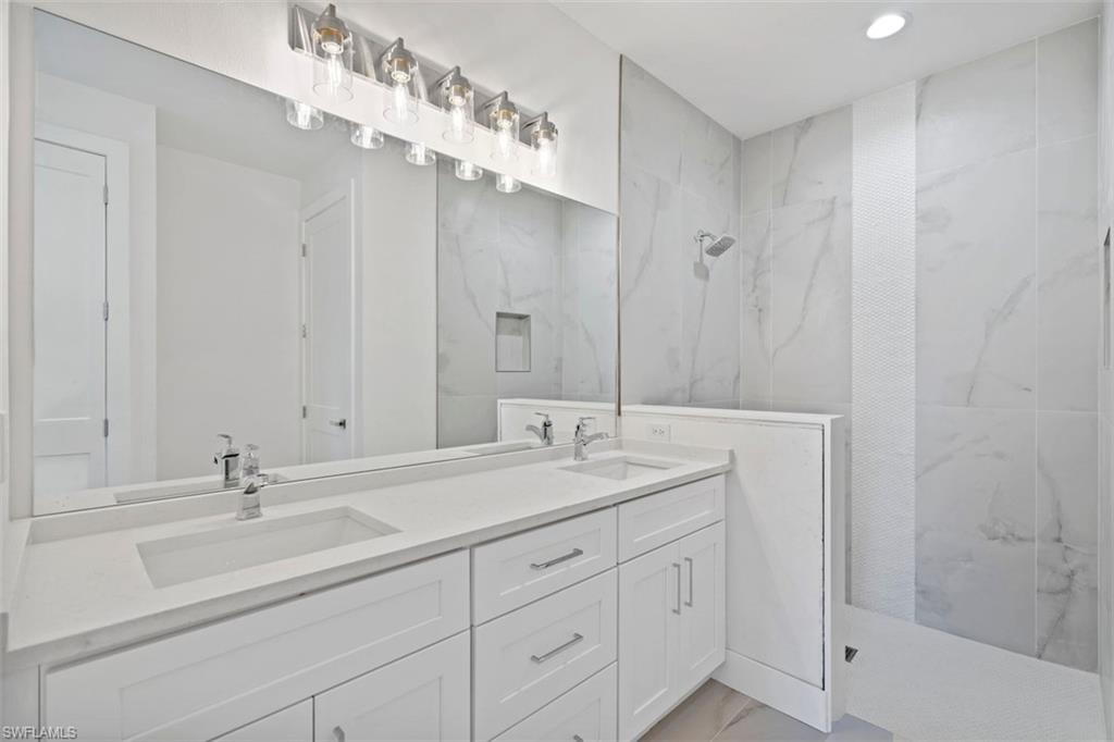 Full bathroom with a marble finish shower, marble finish floor, a sink, and double vanity