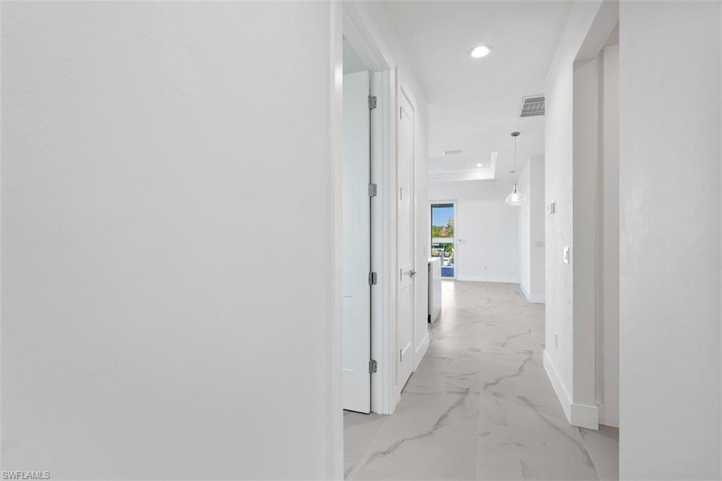 Corridor featuring baseboards, marble finish floor, visible vents, and recessed lighting