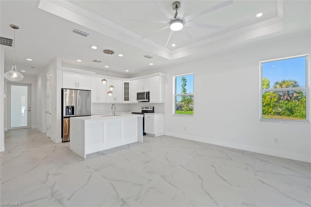 Kitchen featuring stainless steel appliances, recessed lighting, a raised ceiling, glass insert cabinets, and a sink