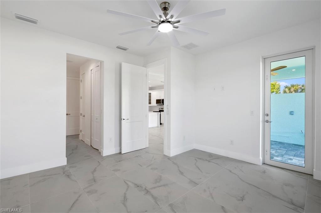 Empty room with marble finish floor, baseboards, visible vents, and a ceiling fan