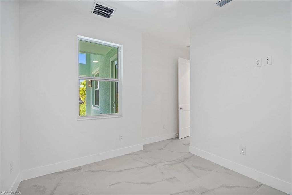 Unfurnished room featuring baseboards, marble finish floor, and visible vents