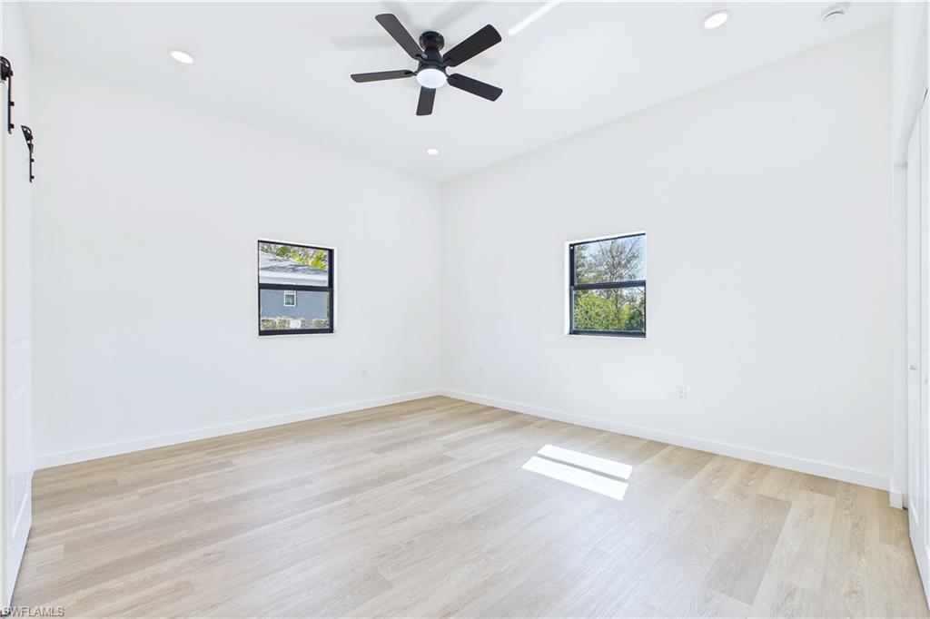Spare room featuring plenty of natural light, a barn door, light wood-type flooring, ceiling fan, and recessed lighting