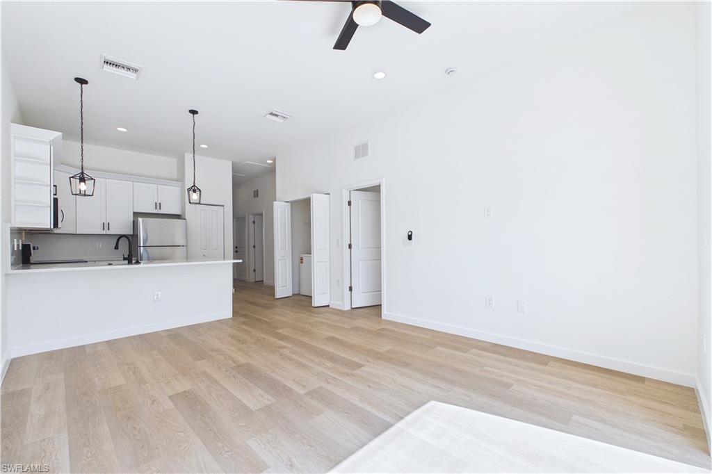 Unfurnished living room with light wood-style floors, ceiling fan, and recessed lighting