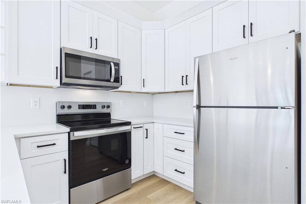 Kitchen featuring stainless steel appliances, white cabinets, and light wood-style flooring