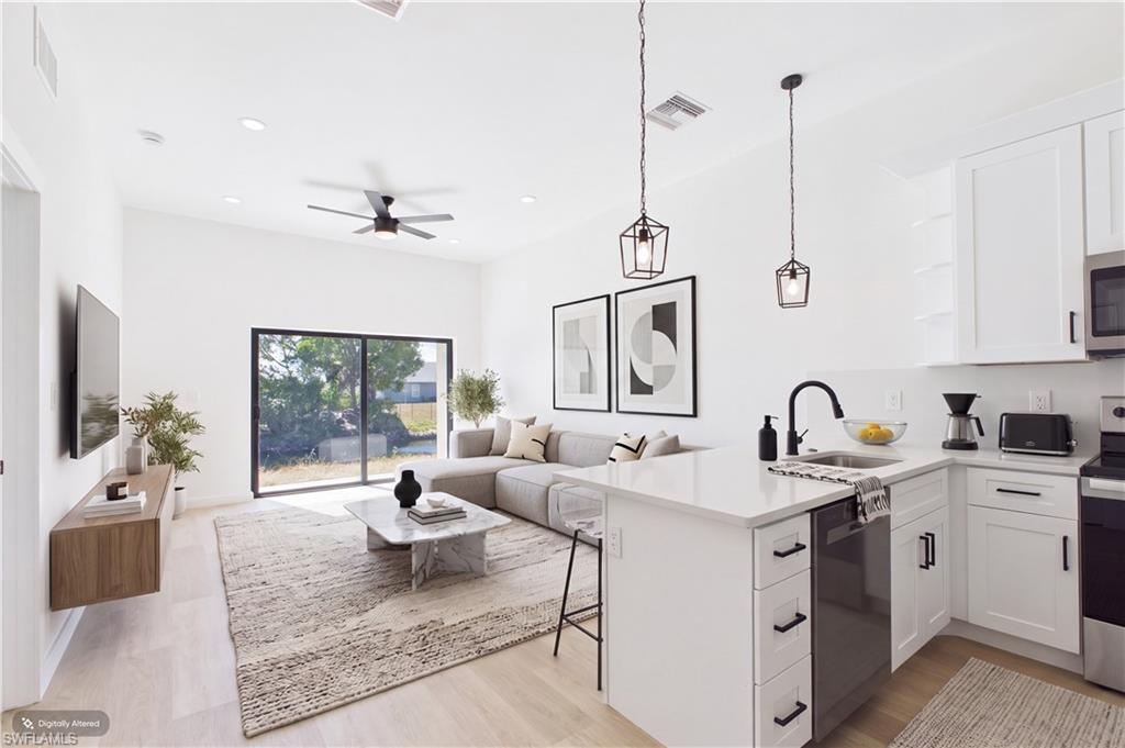 Open-concept living space featuring a modern kitchen island with seating, pendant lighting, white shaker cabinetry, and a sliding glass door to the exterior
