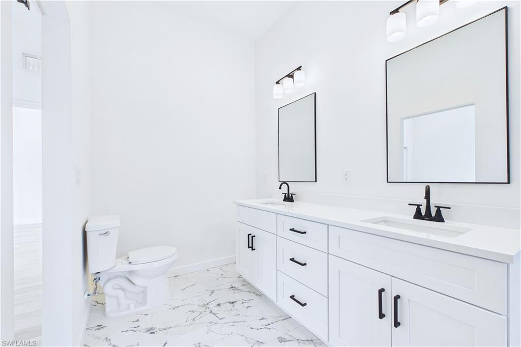 Bathroom featuring double vanity and light marble finish flooring